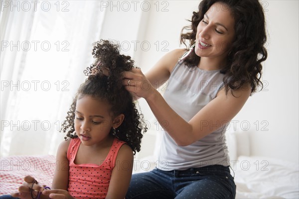 Mother styling hair of daughter