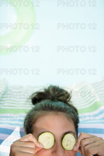 Caucasian woman with cucumbers on eyes