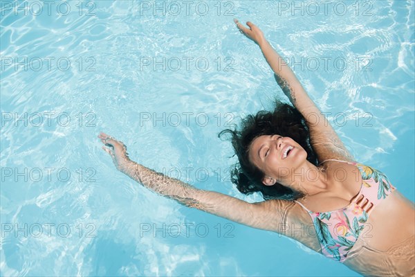 Caucasian woman floating in swimming pool