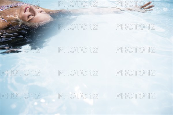 Caucasian woman floating in swimming pool