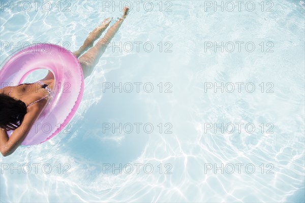 Caucasian woman floating in swimming pool