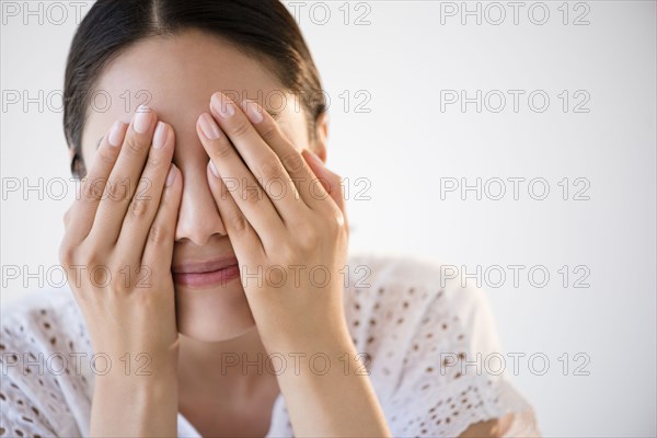 Hispanic woman covering her eyes