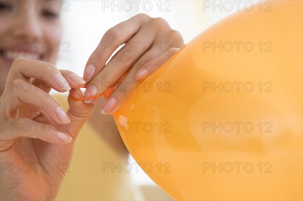 Hispanic woman tying balloon