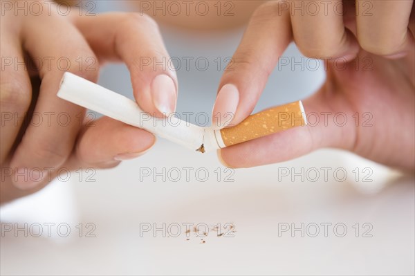 Close up of Hispanic woman breaking cigarette