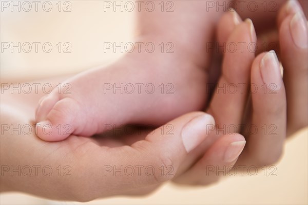 Close up of mother holding bare foot of baby