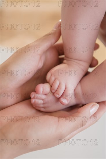 Close up of mother holding bare feet of baby