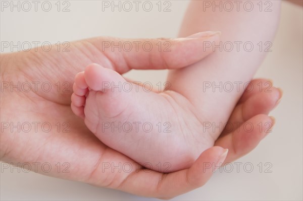 Close up of mother holding bare foot of baby