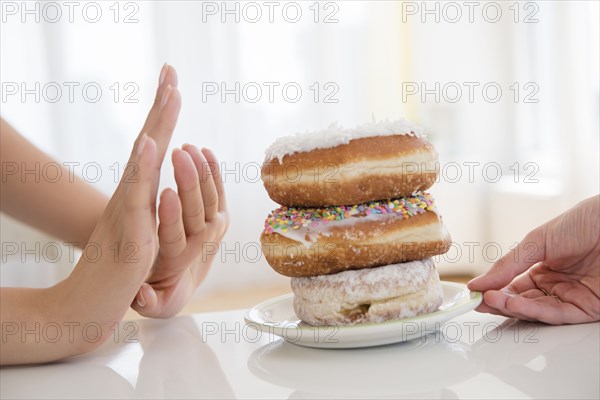 Woman refusing plate of donuts