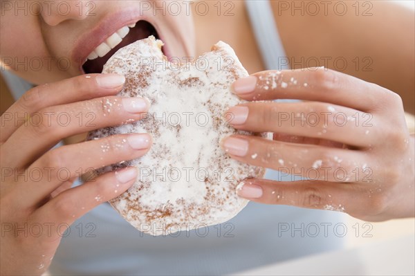 Close up of Hispanic woman eating donut