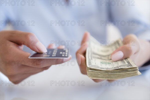 Hispanic woman holding cash and credit card