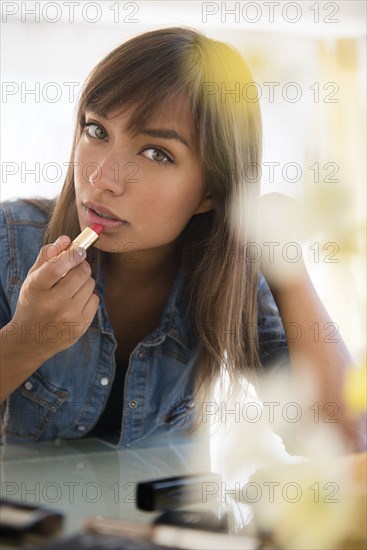 Mixed race woman applying lipstick