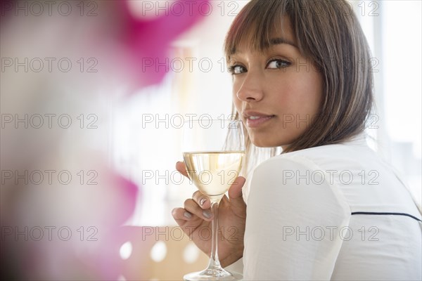 Mixed race woman drinking white wine