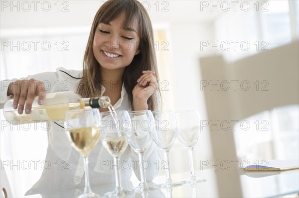 Mixed race woman pouring white wine