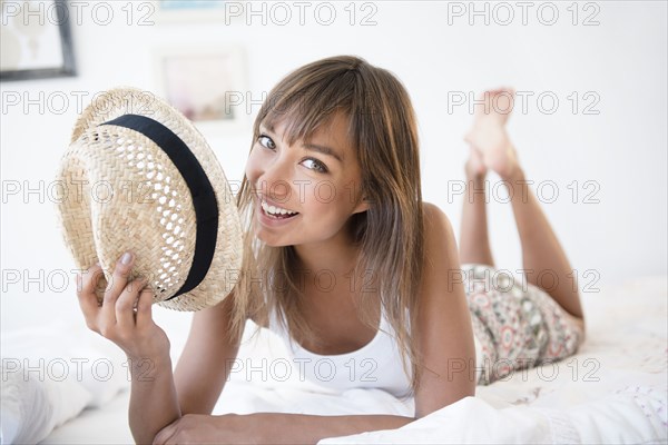 Mixed race woman with straw hat on bed