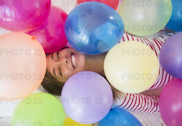 Mixed race woman playing in balloons