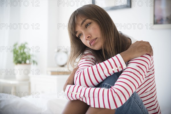 Mixed race woman hugging her knees