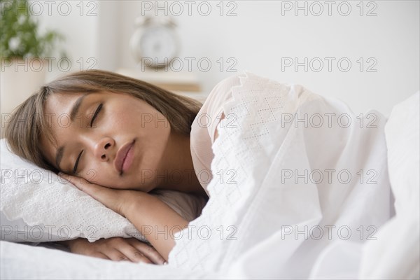 Mixed race woman sleeping in bed