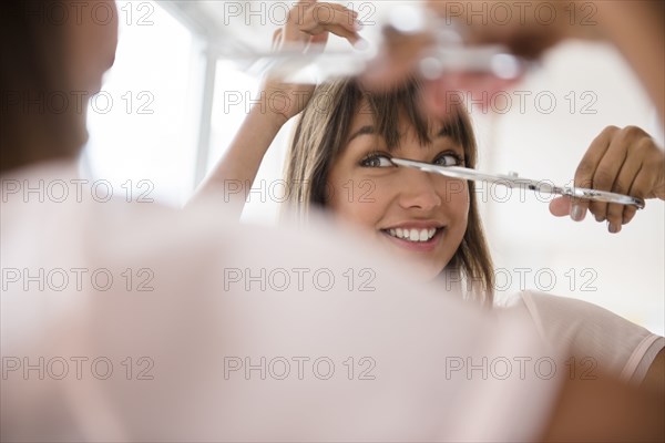 Mixed race woman trimming her bangs