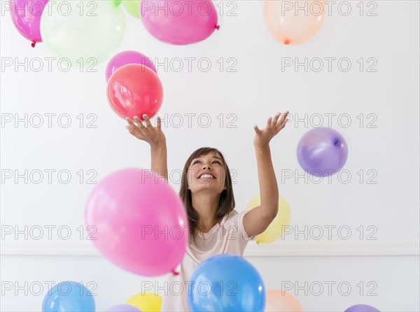 Mixed race woman playing with balloons