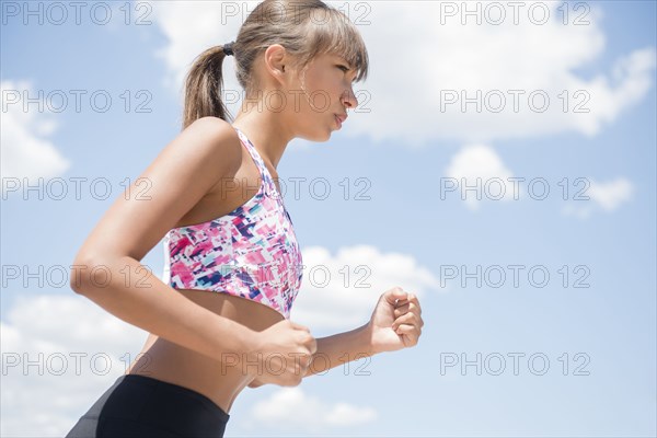 Mixed race woman jogging under blue sky