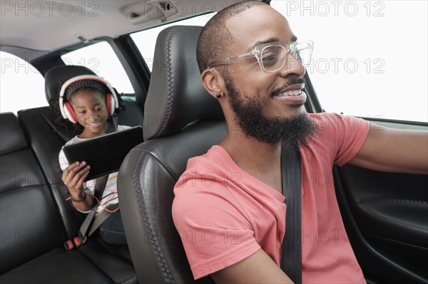 Black father and daughter driving in car