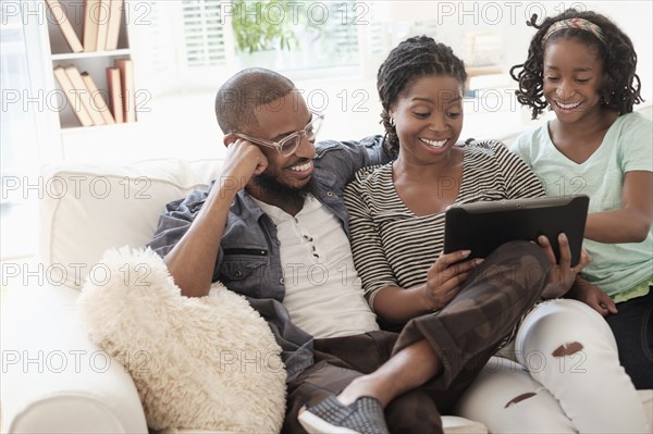 Black family using digital tablet on sofa