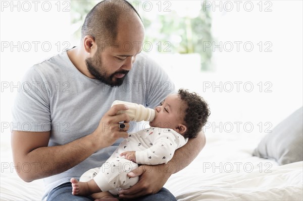 Father bottle feeding baby son