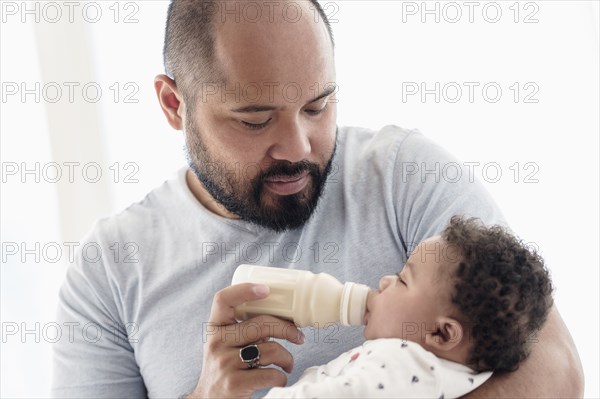 Father bottle feeding baby son