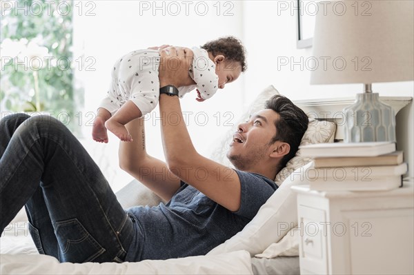 Father holding baby son on bed