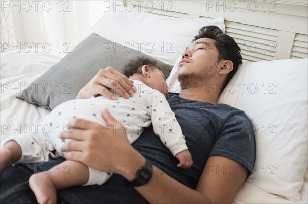 Father and baby son sleeping on bed