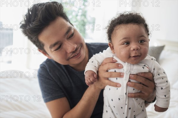 Father holding baby son on bed