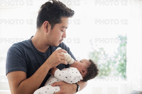 Father bottle feeding baby son