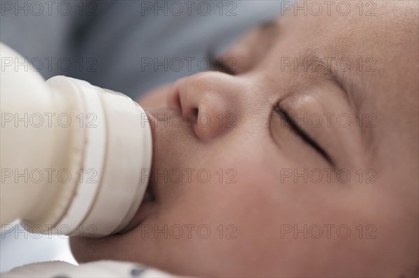 Close up of mixed race boy bottle feeding