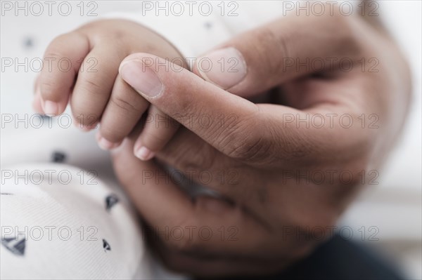 Close up of father holding hand of baby son