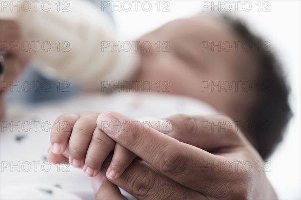 Close up of father holding hand of baby son