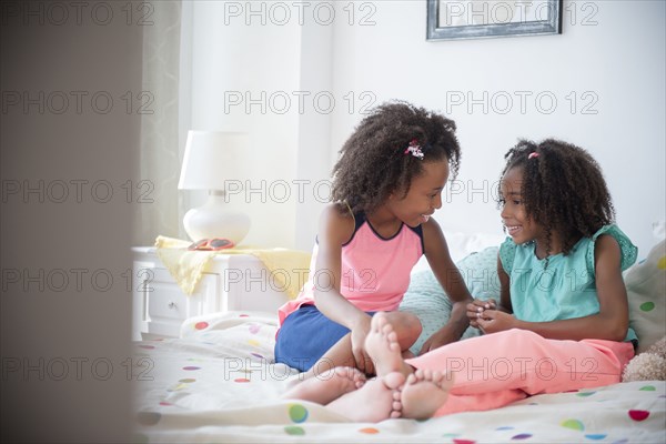 Mixed race sisters talking on bed