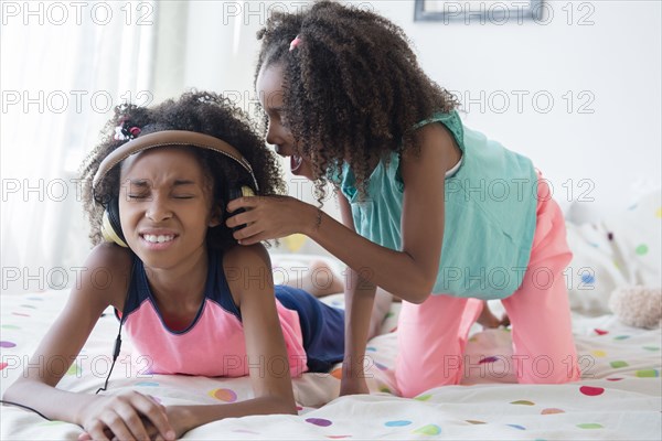 Mixed race girl bothering sister on bed