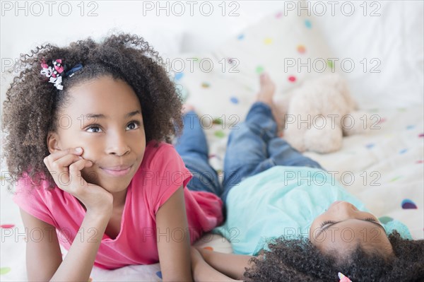Mixed race sisters laying on bed