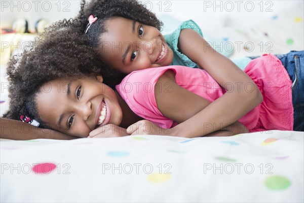 Mixed race sisters laying on bed