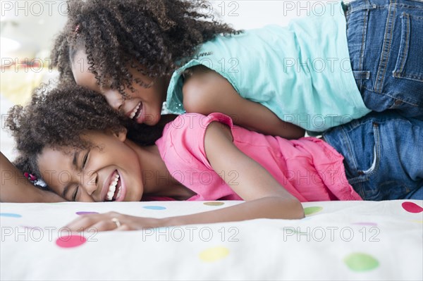 Mixed race sisters playing on bed