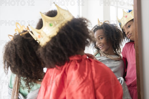 Mixed race sisters playing dress up in mirror