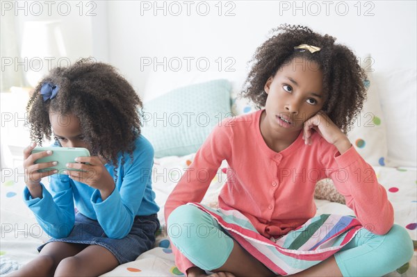 Bored mixed race girl sitting on bed