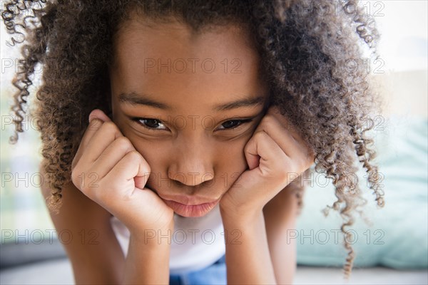 Moody mixed race girl resting chin in hand