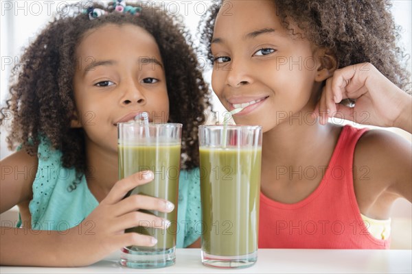 Mixed race sisters drinking healthy juice