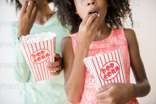 Mixed race sisters eating popcorn