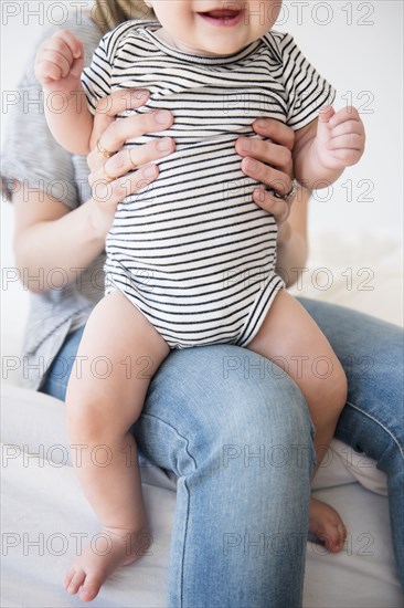 Caucasian mother holding baby daughter on bed