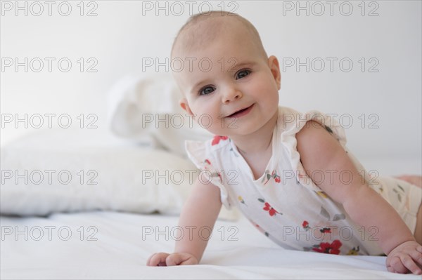 Caucasian baby girl crawling on bed