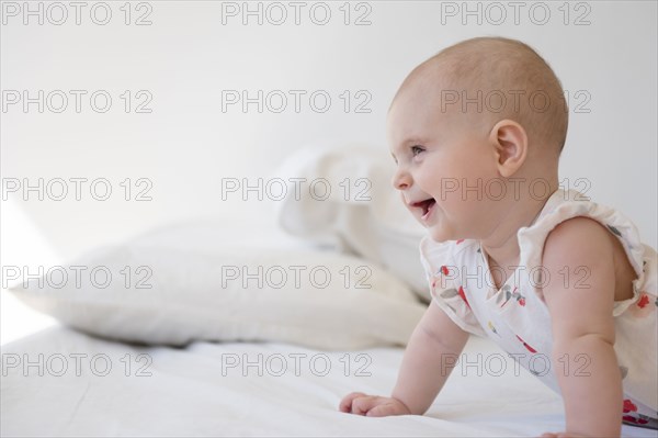 Caucasian baby girl crawling on bed