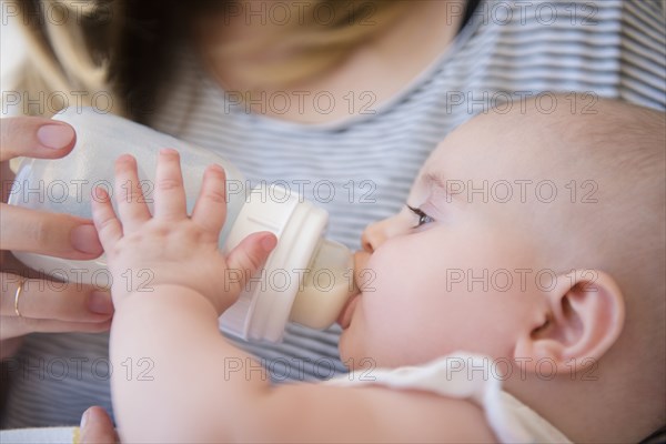 Caucasian mother feeding baby daughter