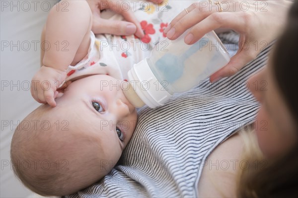 Caucasian mother feeding baby daughter